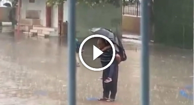 Dede torununu sırtına alarak yağmur altında İstiklal Marşı okudu